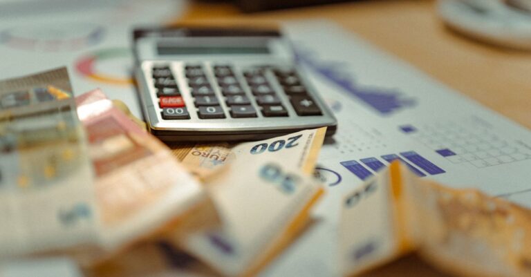 Euro banknotes and calculator on financial documents, focusing on business budget planning.